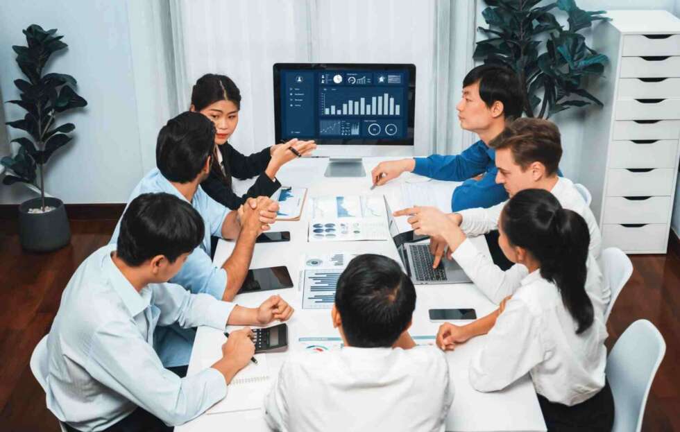 Business team collaborating during a meeting using Microsoft 365 for business to review reports, share data, and improve productivity.